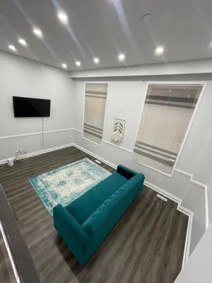 a living room with a blue couch and a flat screen tv at Triple M Lodge Master Bedroom in Mississauga