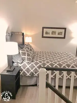 a bedroom with a bed and a table with a lamp at Blue Mountain, Collingwood - Loft Condo, sleeps 4 in Blue Mountains