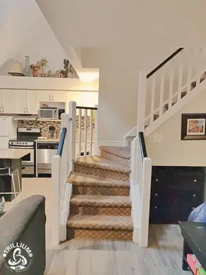 a living room with a staircase and a kitchen at Blue Mountain, Collingwood - Loft Condo, sleeps 4 in Blue Mountains