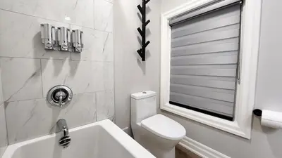 a bathroom with a toilet and a sink and a window at The Zen Escape Modern Queen Size One Bedroom Full Apartment in St. Catharines