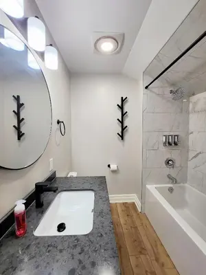 a bathroom with a sink and a tub and a mirror at The Zen Escape Modern Queen Size One Bedroom Full Apartment in St. Catharines