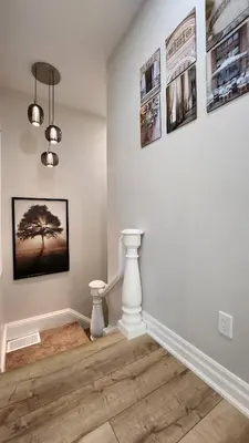 a room with a white wall with pictures on the wall at The Zen Escape Modern Queen Size One Bedroom Full Apartment in St. Catharines