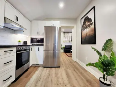 a kitchen with white cabinets and a stainless steel refrigerator at The Zen Escape Modern Queen Size One Bedroom Full Apartment in St. Catharines