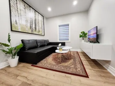 a living room with a black couch and a table at The Zen Escape Modern Queen Size One Bedroom Full Apartment in St. Catharines