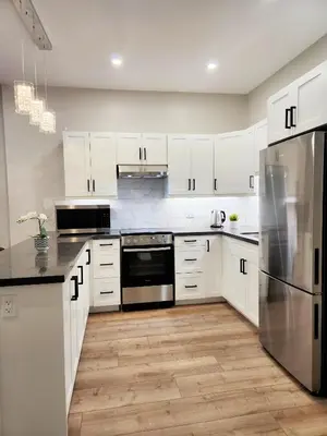 a kitchen with white cabinets and a stainless steel refrigerator at The Zen Escape Modern Queen Size One Bedroom Full Apartment in St. Catharines