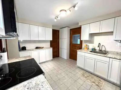 a kitchen with white cabinets and a black counter top at Vintage cute house 5 min from the beautiful Falls! in Niagara Falls