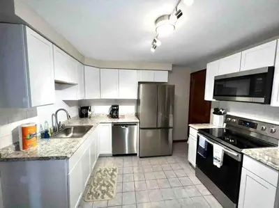 a kitchen with white cabinets and stainless steel appliances at Vintage cute house 5 min from the beautiful Falls! in Niagara Falls