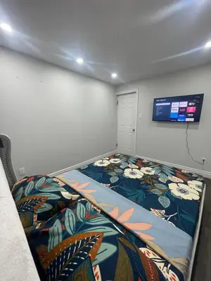 a room with a bed with a tv on the wall at Mo's Place in Mississauga
