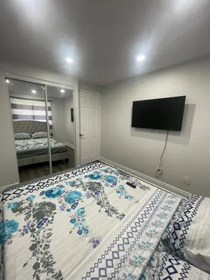 a bedroom with a bed with a television on the wall at Mo's Place in Mississauga