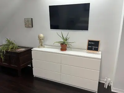 a white dresser with a flat screen tv on a wall at Bright, Private, Peaceful Suite with Retail Conveniences Steps Away in Toronto