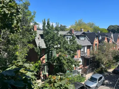 a row of houses with a car parked in the street at Bright, Private, Peaceful Suite with Retail Conveniences Steps Away in Toronto