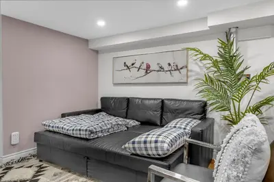 a black leather couch in a living room with a plant at Modern 2BR on Queensway, Kitchen, Parking, 20 Mins from CNT and YYZ in Toronto