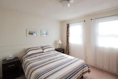 a bedroom with a bed with a striped comforter and a window at The Comfort Stay at City of Pickering in Pickering