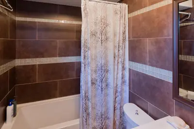 a bathroom with a tub and a shower curtain at The Comfort Stay at City of Pickering in Pickering