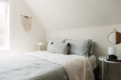a white bedroom with a bed and a window at The Beachside Burrow - Next to Sandbanks w Hot Tub in West Lake