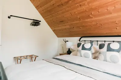 a bedroom with a white bed with a wooden ceiling at The Beachside Burrow - Next to Sandbanks w Hot Tub in West Lake