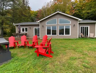 a group of red chairs sitting in a yard at Four Season Waterfront Muskoka Retreat in Bracebridge