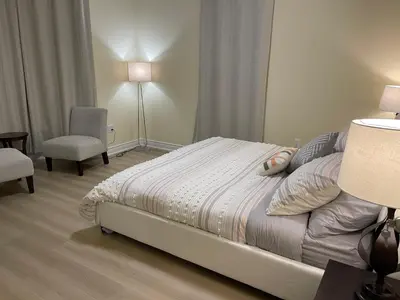 a bedroom with a bed and a chair and a lamp at Victoria Family Vacation Home - King Bed Private Yard BBQ Deck Gazebo - 4 Minutes To The Falls in Niagara Falls