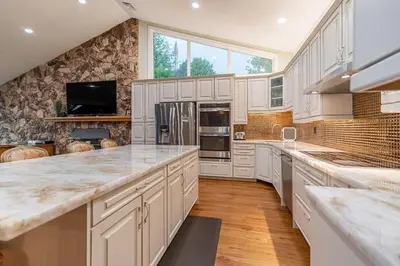 a large kitchen with white cabinets and marble counter tops at Waterfront - Kawartha Lakes in Kawartha Lakes