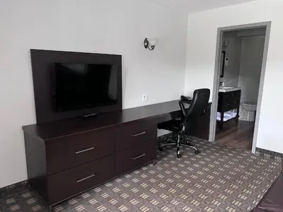 a room with a desk with a television and a chair at Wellington Inn in Bracebridge