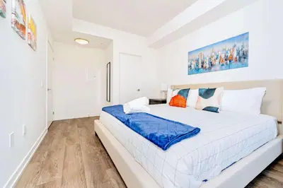 a white bedroom with a large bed in it at Union Towers Condo with City Views and Patio in Kitchener