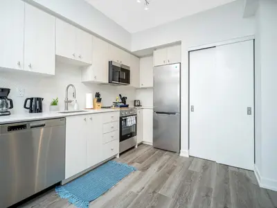 a kitchen with white cabinets and a stainless steel refrigerator at Modern 1BR Condo - King bed - Cityscape Views in Kitchener