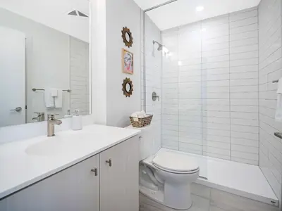 a white bathroom with a toilet and a shower at Modern 1BR Condo - King bed - Cityscape Views in Kitchener