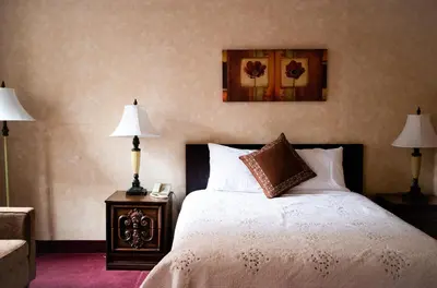 a bedroom with a bed with two lamps and a picture on the wall at Royal Inn and Suites at Guelph in Guelph