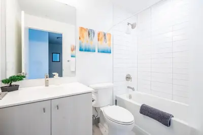 a white bathroom with a toilet and a tub and a sink at 1BR Modern Condo - King Bed and Stunning City View in Kitchener