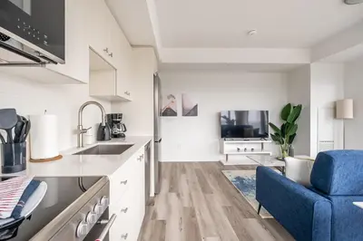 a kitchen with a sink and a blue chair at 1BR Modern Condo - King Bed and Stunning City View in Kitchener
