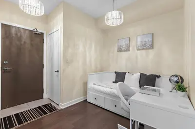 a white bedroom with a bed and a desk and chandeliers at Ultra Luxurious 2.5 Bedroom 2 Full Bathroom 1 Parking Condo Near SQ1 Striking Views in Mississauga
