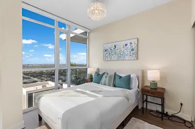 a bedroom with a large bed and a large window at Ultra Luxurious 2.5 Bedroom 2 Full Bathroom 1 Parking Condo Near SQ1 Striking Views in Mississauga