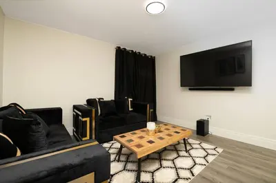 a living room with two black couches and a table at Stylish House W a Media Room Near Downtown Picton in Picton