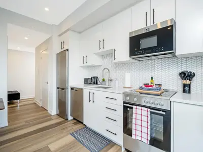 a kitchen with white cabinets and a stove top oven at City View 1BR Condo - King Bed & Private Balcony in Kitchener