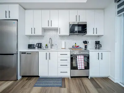 a kitchen with white cabinets and stainless steel appliances at City View 1BR Condo - King Bed & Private Balcony in Kitchener