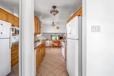 a kitchen with wooden cabinets and a white refrigerator at Glengarry Haus Spacious 2BR Home Away From Home in Mississauga