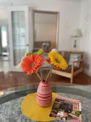a red vase with flowers on a glass table at Glengarry Haus Spacious 2BR Home Away From Home in Mississauga