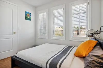 a bedroom with a bed with white walls and windows at The cozy corner House in the Richmond Hill in Richmond Hill