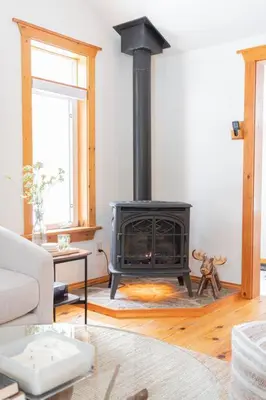 a living room with a black stove in a room at The Doma Lodge - Cozy Muskoka Cabin in the Woods in Huntsville