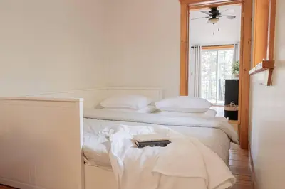 a bedroom with two beds with white sheets and a window at The Doma Lodge - Cozy Muskoka Cabin in the Woods in Huntsville