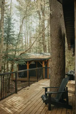 a wooden deck with a bench next to a tree at The Doma Lodge - Cozy Muskoka Cabin in the Woods in Huntsville