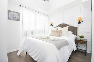 a white bedroom with a large white bed and a window at The Splendid - Luxury 1BR Uptown Toronto in Toronto