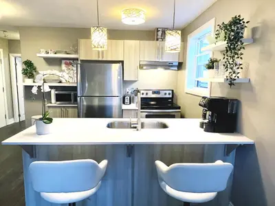a kitchen with a sink and two white chairs at The Cosmopolitan in Wortley Village in London