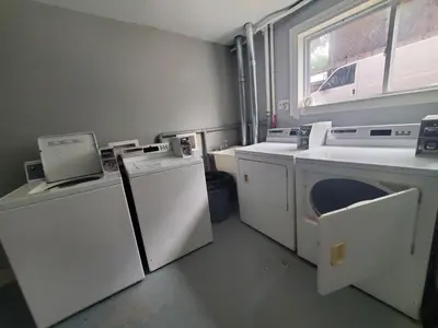 a laundry room with white appliances and a window at The Cosmopolitan in Wortley Village in London