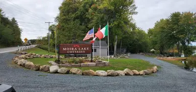 a sign for a north lake conflicts with two flags at Moira Lake Cottages in Madoc
