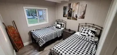 a bedroom with two beds with black and white sheets at Moira Lake Cottages in Madoc