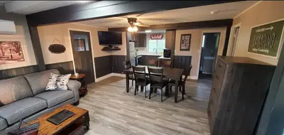 a living room with a couch and a table and a kitchen at Moira Lake Cottages in Madoc