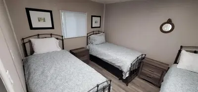 a bedroom with two beds and a mirror on the wall at Moira Lake Cottages in Madoc