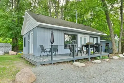 a small white shed with a table and chairs at Moira Lake Cottages in Madoc