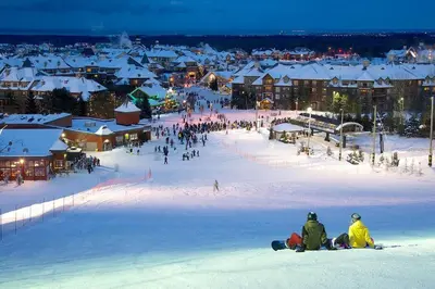 a group of people sitting in the snow in a town at Luxury 2 Level Mountain Walk Condo Sauna Jacuzzi Walk to Village in Blue Mountains